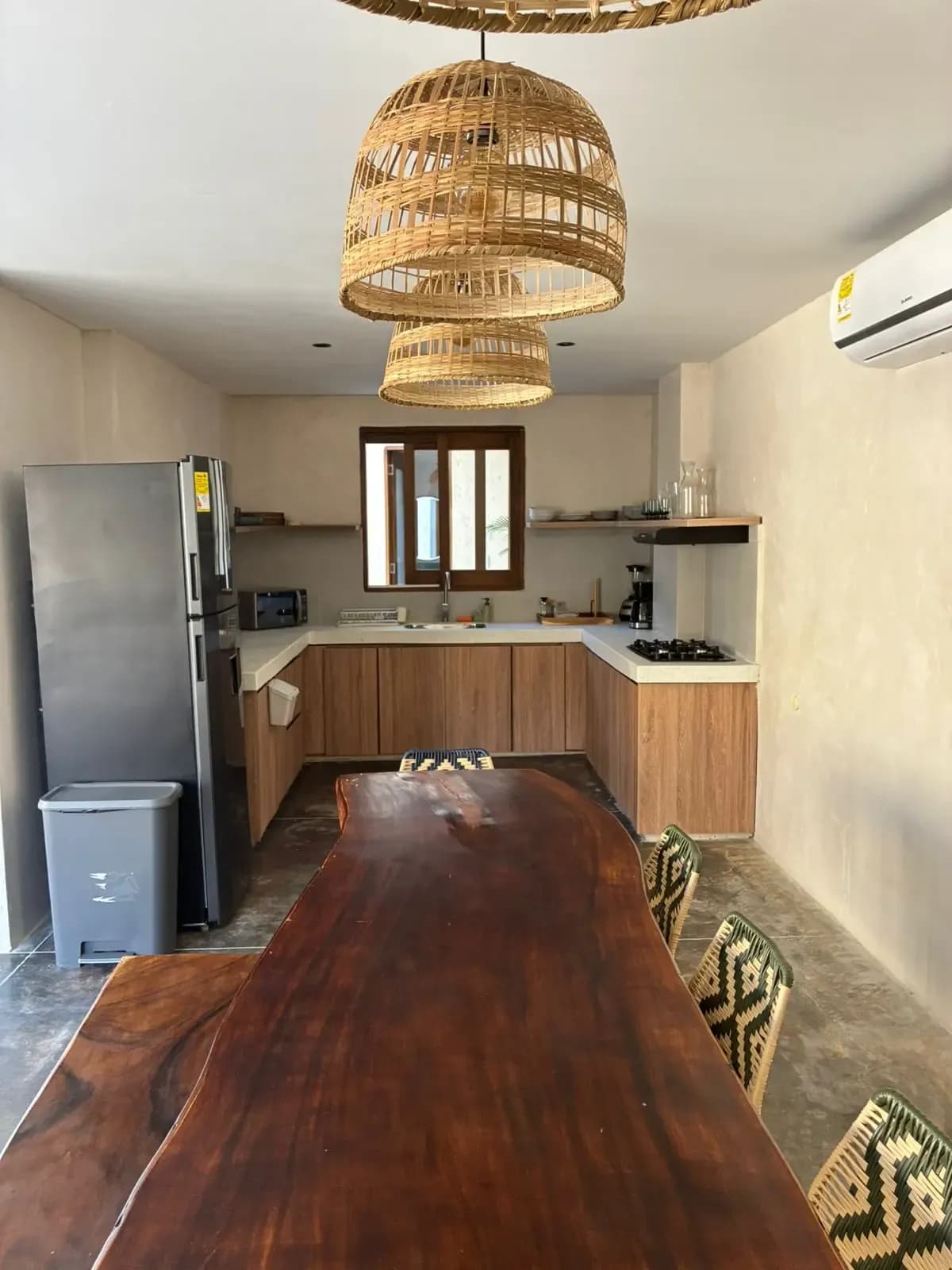 Cocina y comedor con mesa de madera maciza, lamparas colgantes y estanteria abierta