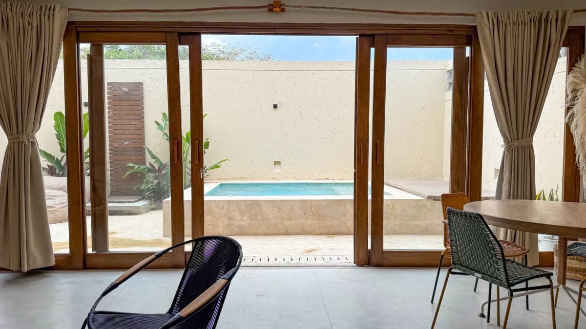 Vista a traves de puertas de vidrio desde el interior hacia el patio con piscina