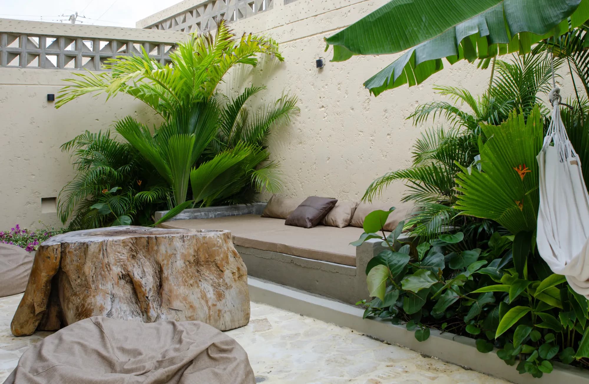 Casa de dos pisos color arena con detalles de calados, jardin tropical y camino curvo de piedra